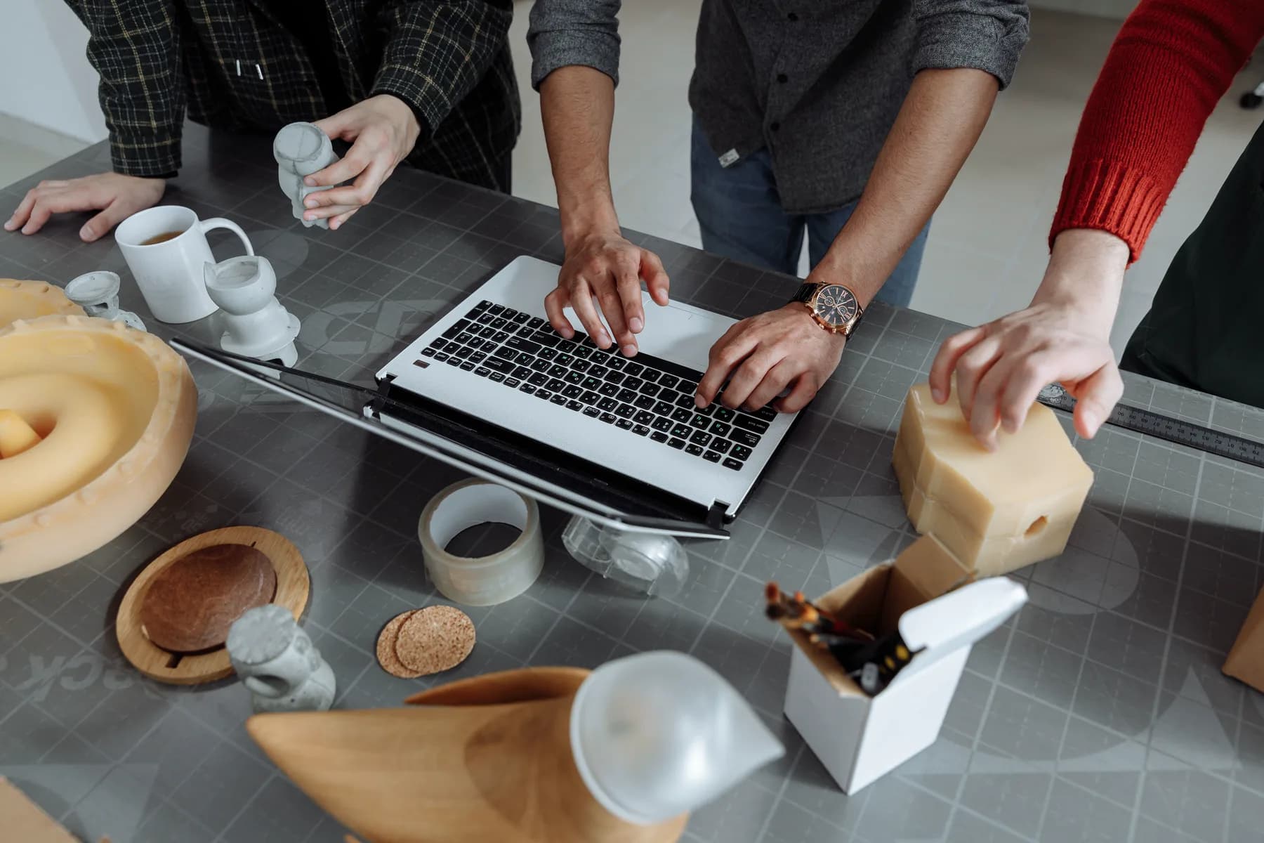 Product team reviewing physical prototypes and design work around a laptop